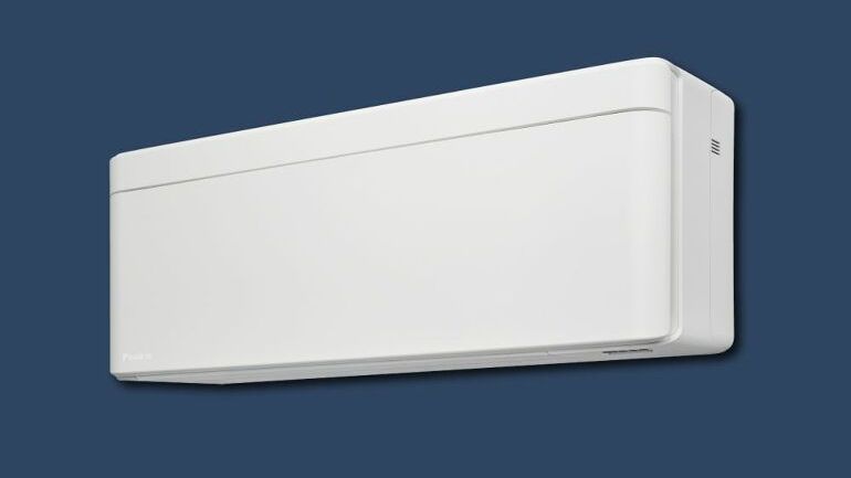 Veggmontert innedel fra Daikin i stilrent hvitt design mot blå bakgrunn.