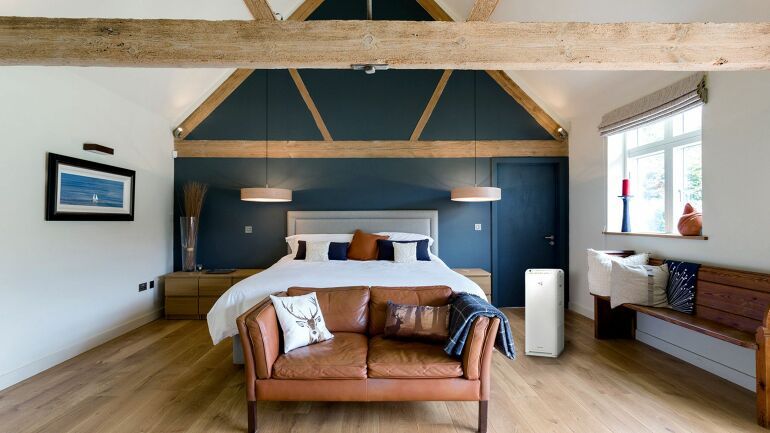 Moderne soverom med synlig Daikin luftrenser plassert i hjørnet ved sengen.